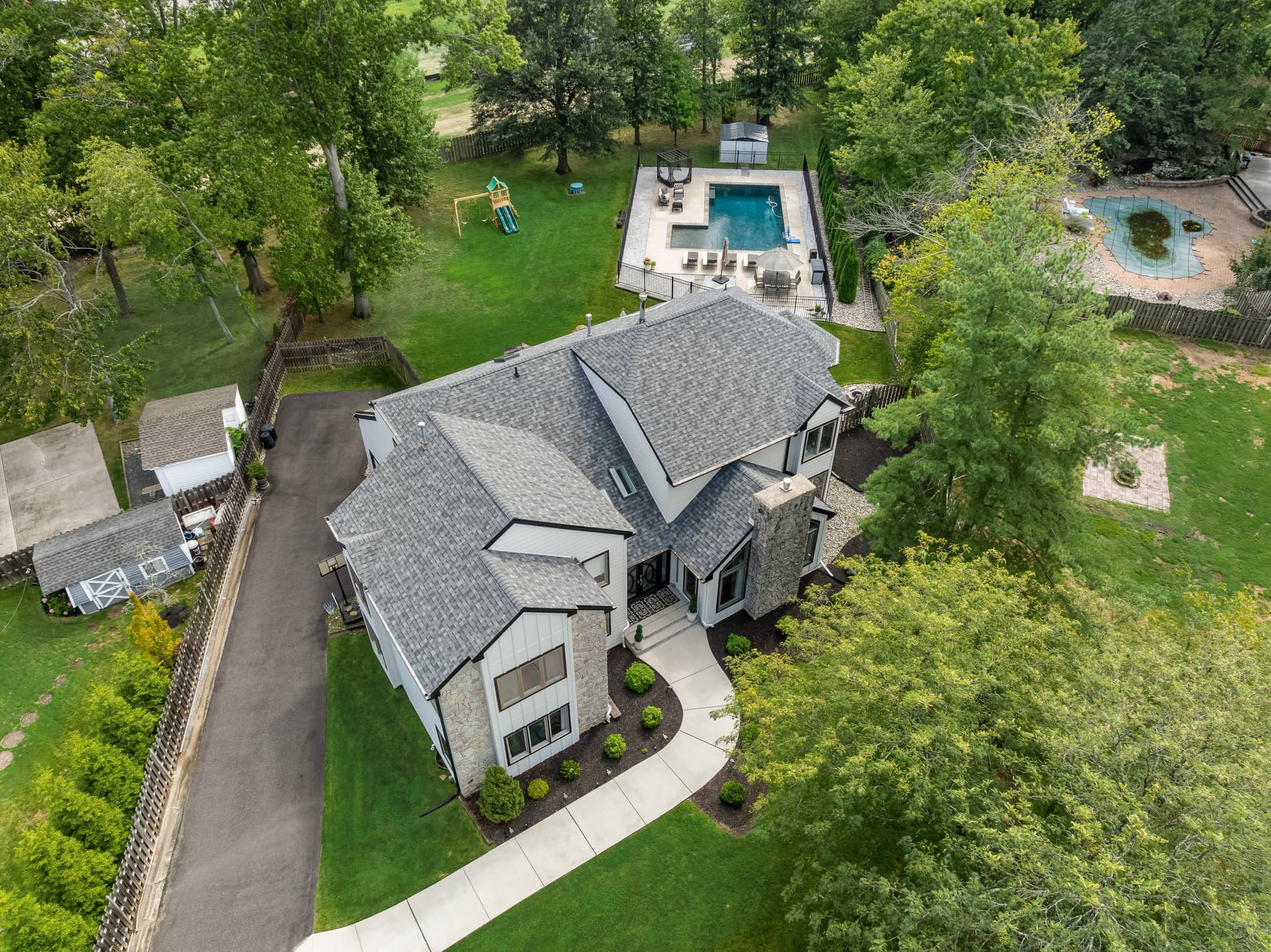 Drone photo of a modern home with a backyard pool and play set, Cherry Hill, NJ