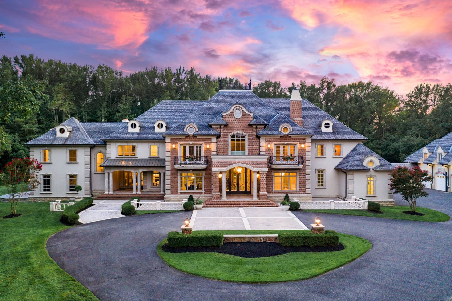 Twilight photography of a French-style brick and stucco estate glowing at dusk in Mount Laurel, NJ
