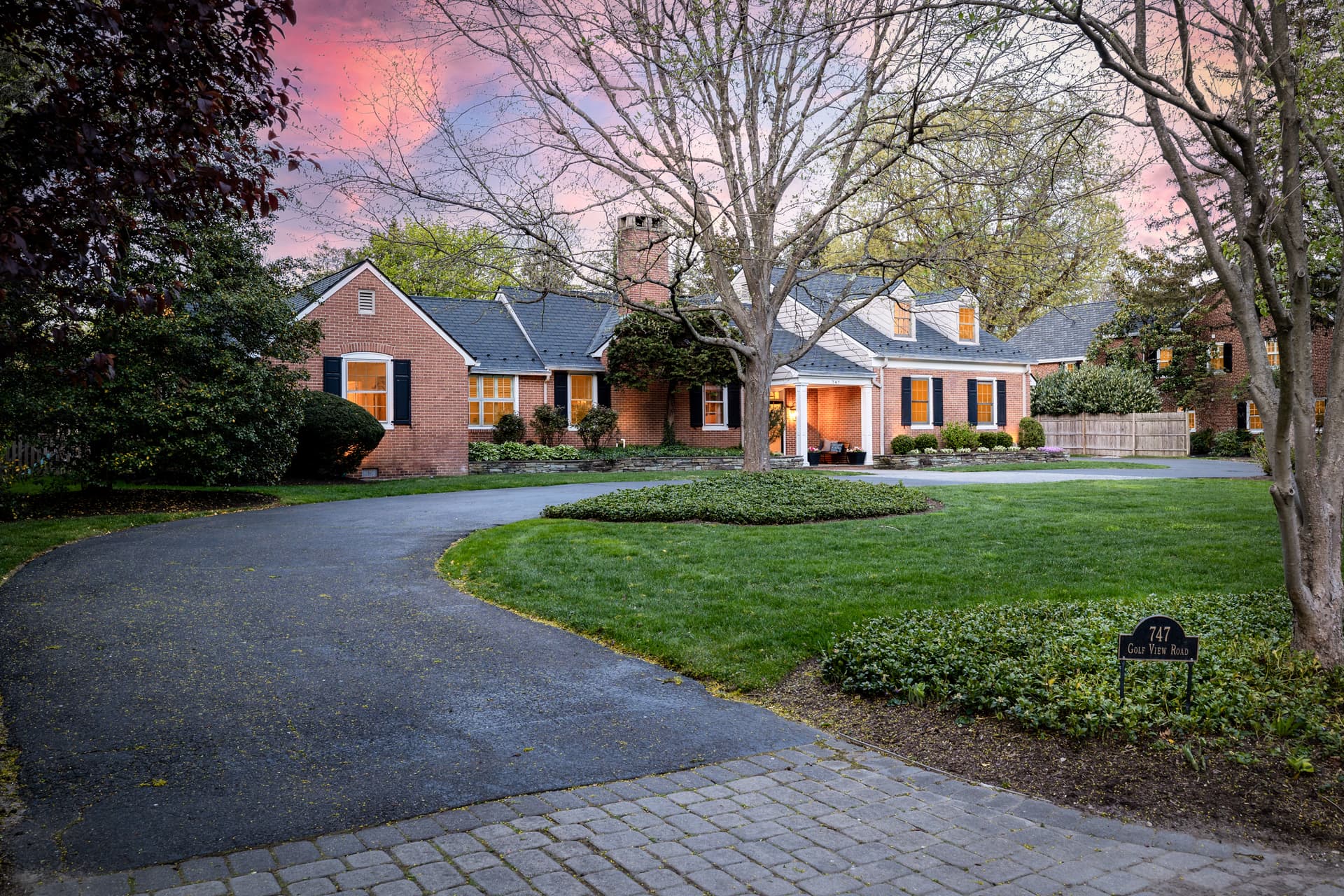 Twilight photography of a brick Cape Cod home glowing at dusk in Moorestown, NJ