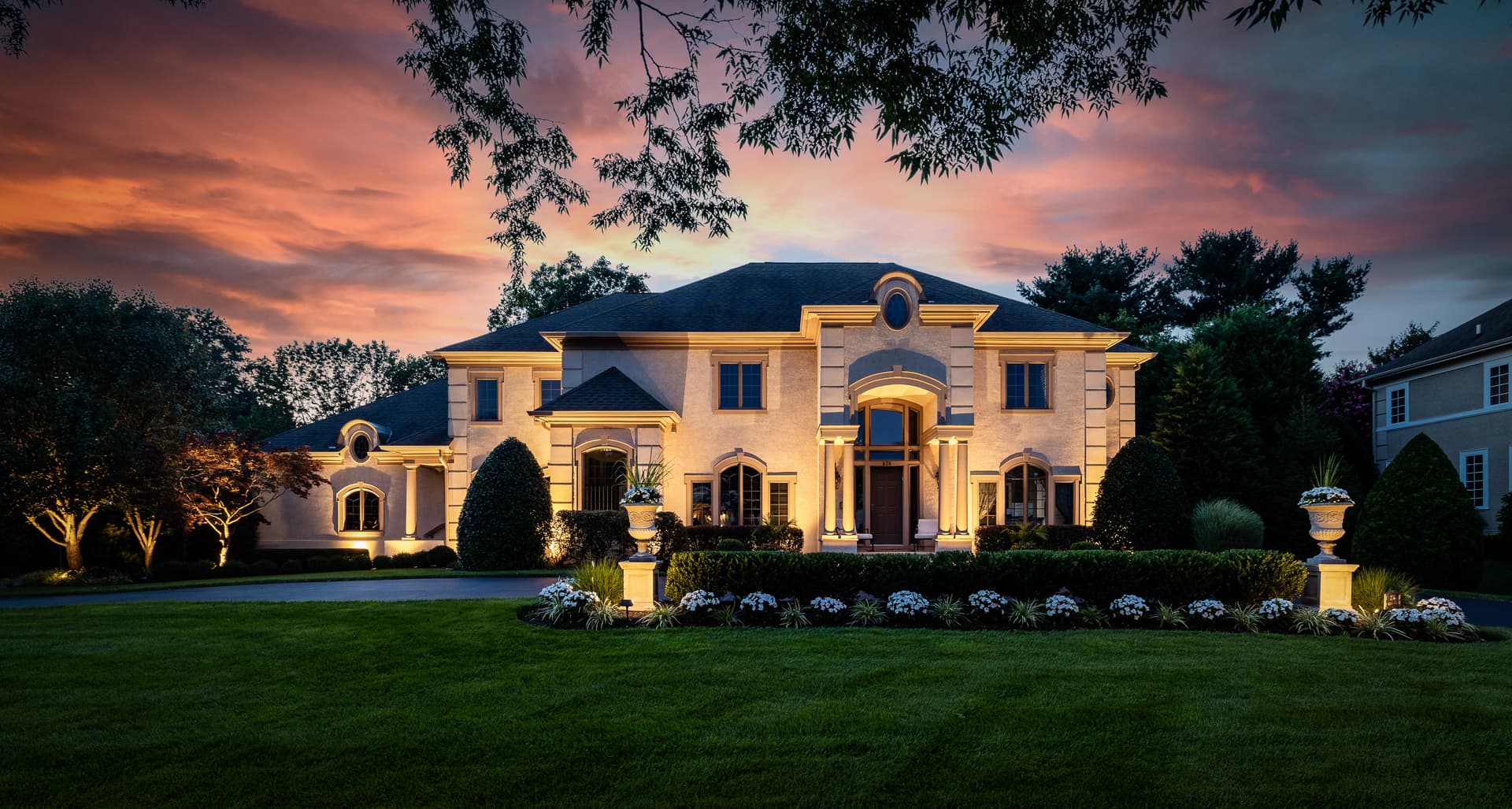 Twilight photography of a grand stucco estate glowing at dusk under a dramatic sky, South Jersey